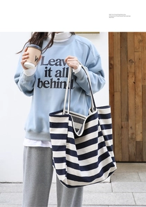 Detail of blue and white striped canvas tote bag held by a model in casual street style