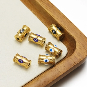 Detailed view of golden evil eye beads with blue enamel on a wooden jewelry display