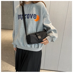 Detail showing the black Oxford fabric shoulder bag on a model wearing a grey sweatshirt