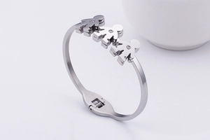 Detail view of silver metal bracelet with three small figures and sparkling accents
