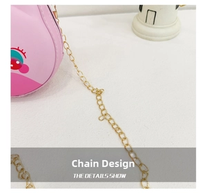 Detailed close-up of a pink cartoon crossbody bag featuring a gold chain strap