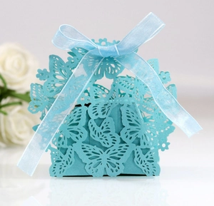 Detail of laser-cut butterfly candy box in sky blue with ribbon bow on white desk