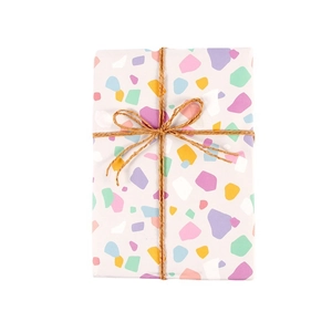 Papel de regalo minimalista con motivo de terrazo y lazo decorativo de cordel de yute.