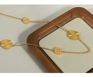 Detailed close-up of a gold necklace featuring textured round charms and crystal accents
