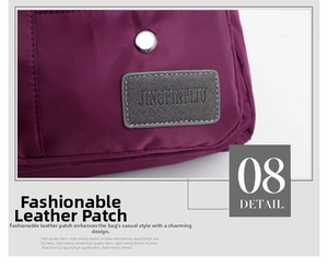 Detail of silver snap button and grey leather logo patch on purple Oxford fabric bag