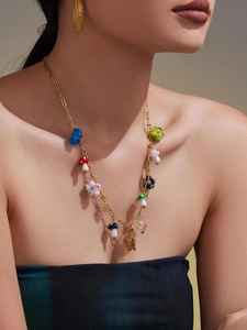 Detail of vintage gold paperclip necklace with colorful resin flower and mushroom charms