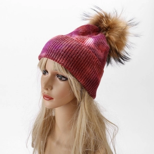 Detail of gradient ribbed knit beanie featuring a large brown faux fur pom pom decoration