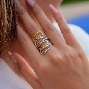 Close-up of dual-tone wavy spiral ring in gold and silver on female model's hand