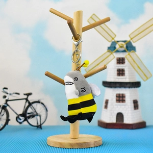 Close-up detail of a funny shark-bee hybrid plush keychain on a wooden display stand