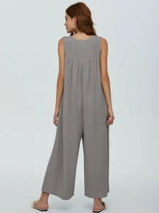 Detail of grey knitted sleeveless jumpsuit featuring a back pleat and wide leg design