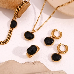Detail von 18K vergoldetem Schmuckset mit schwarzen Onyxherzen auf Steinuntergrund
