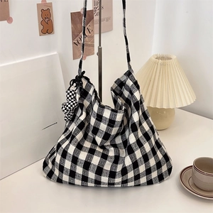 Detail of checkered canvas tote bag with matching puff charm in a cozy aesthetic setting