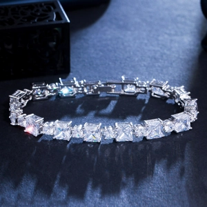 Detailed macro view of square and round zircon gems on a polished silver bracelet band