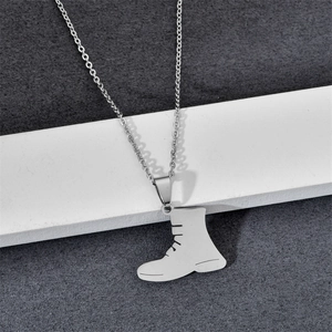 Gros plan d'un collier pendentif botte en argent avec une chaîne fine sur un support