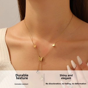 Detail of gold-plated butterfly pendant necklace on model with Y-shaped tassel chain design