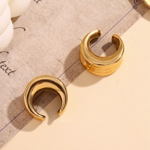 Gros plan détaillé sur des boucles d'oreilles concaves en acier plaqué or 18 carats