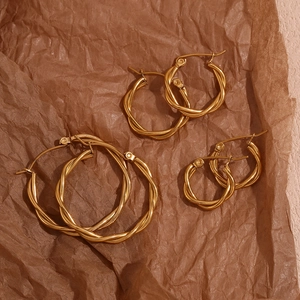 Detailed flat lay of three sizes of twisted 18K gold plated stainless steel hoop earrings
