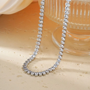 Elegant silver tennis necklace with emerald-cut zircon stones on a glass display
