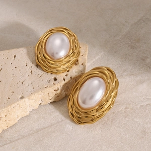 Macro view of vintage style gold spiral edge earrings with large oval pearls on rock