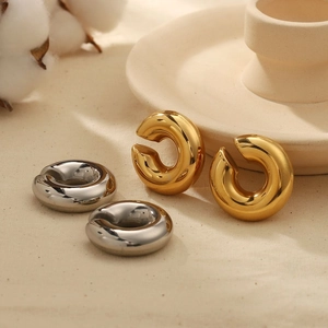 Polished 18K gold and silver chunky C-shaped stainless steel hoop earrings on linen