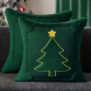 Close-up of green plush pillow covers with yellow embroidered Christmas trees on a sofa