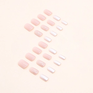 Short press-on nails in soft pink, glitter, and pearl white arranged in an S-curve