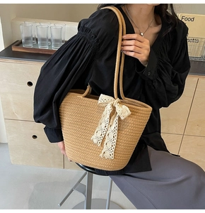 Detailed texture of hand-woven straw tote bag featuring a decorative lace bow accent