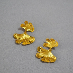 Macro detail of golden ginkgo leaf earrings showing intricate textured vein patterns
