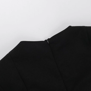 Detailed macro view of invisible back zipper and stitching on black long-sleeve dress