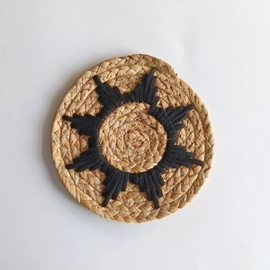 Bohemian round straw wall decor featuring a central black starburst embroidery pattern