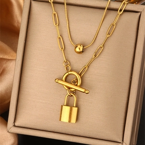 Close-up of double-layer gold chain necklace with padlock pendant and toggle clasp