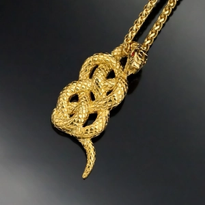 Gold snake pendant necklace with red gemstone eyes and textured scales on black background