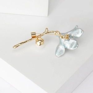 Elegant gold and light blue trumpet flower brooch displayed on a minimalist white base