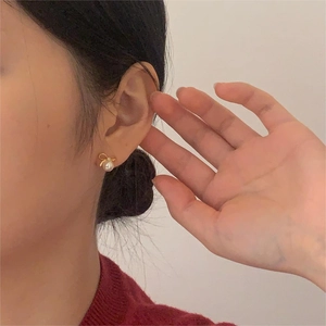 Detailed view of elegant silver bow earrings with round white pearl drops on ear