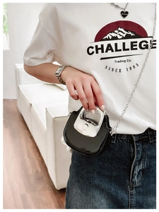 Detail showing mini black glossy crossbody bag with unique U-shaped silver metal handle