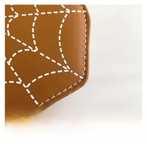 Detalle de costuras de tela de araña blanca sobre superficie de bolso de cuero PU