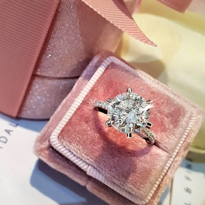 Elegant six-prong solitaire engagement ring with side stones in a pink velvet gift box