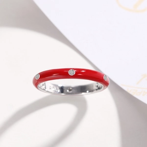 Close-up of red enamel ring with small zircons on a white minimalist background