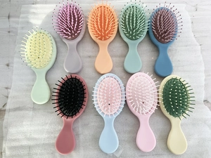 Flat lay of colorful mini travel hairbrushes with soft nylon massage bristles on white