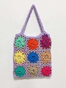 Detail of colorful handmade crochet floral patterns on a violet knit tote shoulder bag