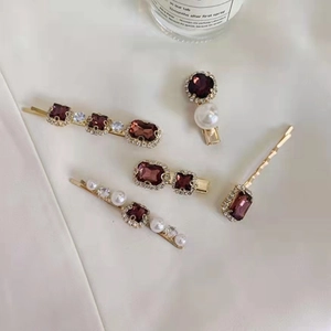 Detail of vintage gold hairpins set with purple gems, pearls and crystals on white silk