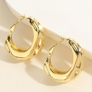 Detailed view of gold metallic chunky C-shaped hoop earrings with unique wavy texture