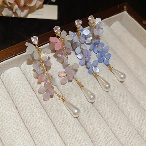 Macro view of floral tassel earrings with zircon studs and teardrop pearls in a jewelry box