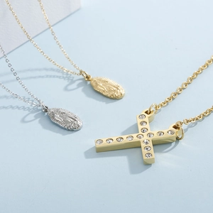 Detailed view of gold and silver Virgin Mary pendants and rhinestone cross on blue background