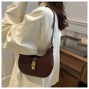 Detail of brown half-moon shoulder bag featuring a vintage gold circular lock and sleek finish