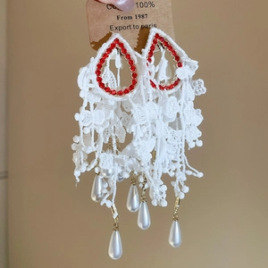 Detail of vintage white lace tassel earrings with ruby rhinestones and faux pearls