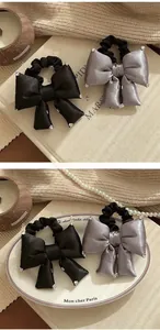Detail of elegant satin bow hair ties with sparkling rhinestones in black and purple