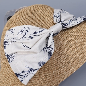 Elegant woven sun hat with large floral bow decoration and wide brim for vacation