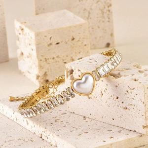 Detail of gold heart bracelet featuring baguette-cut zircons and white mother-of-pearl