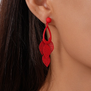 Close-up of red hollow leaf fringe earrings worn by a model showing the matte finish